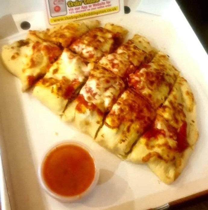 Calzone or stuffed bread topped with cheese and sauce, served with dip.