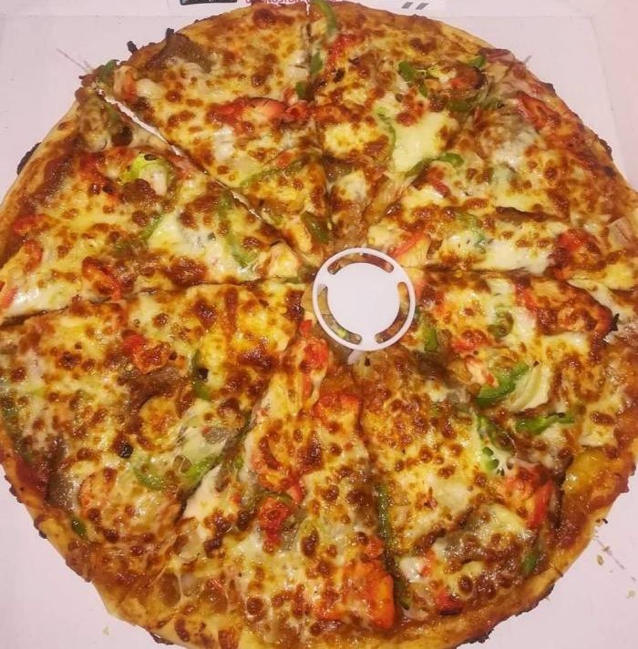 Smash N Grill full sliced pizza in a box, topped with chicken tikka, cheese, and green peppers.